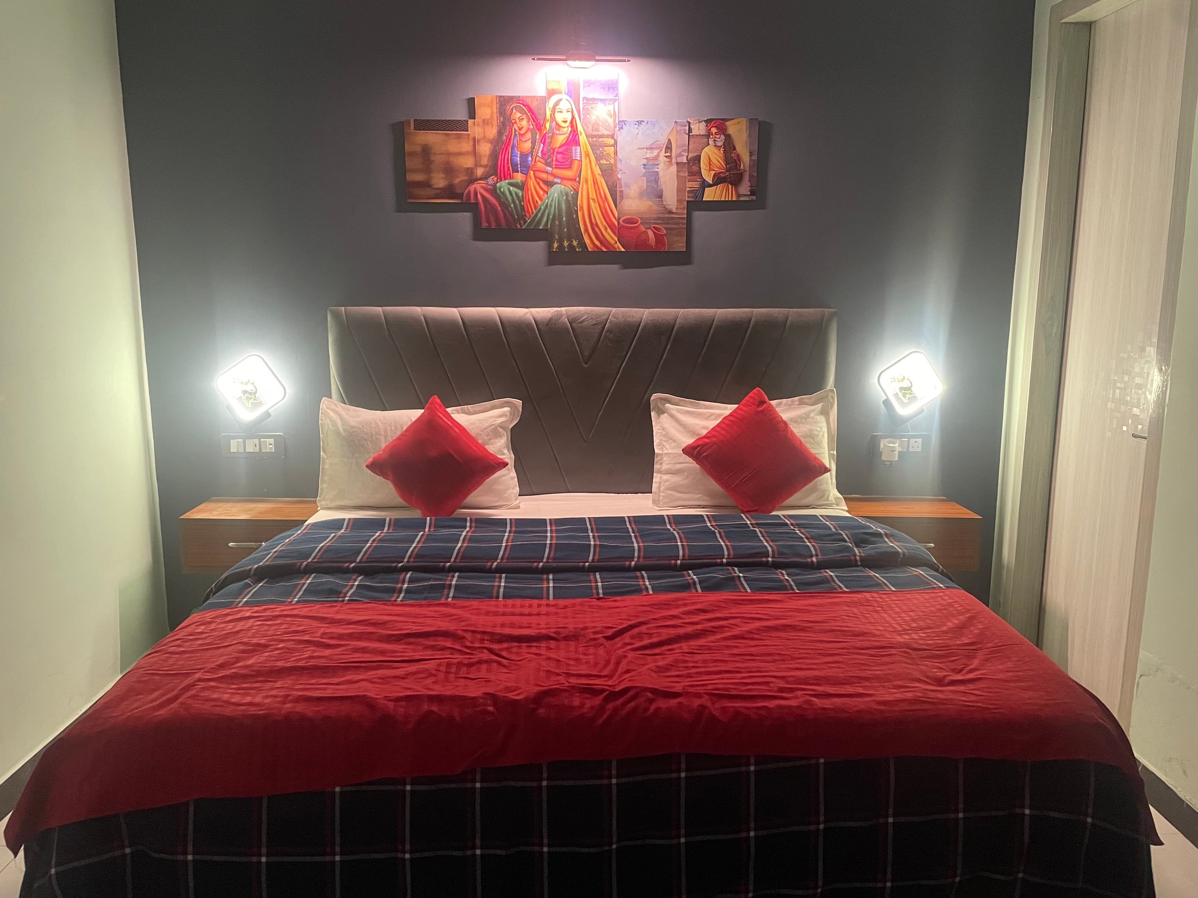 Front view of king bed with navy accent wall and warm LED bedside lamps