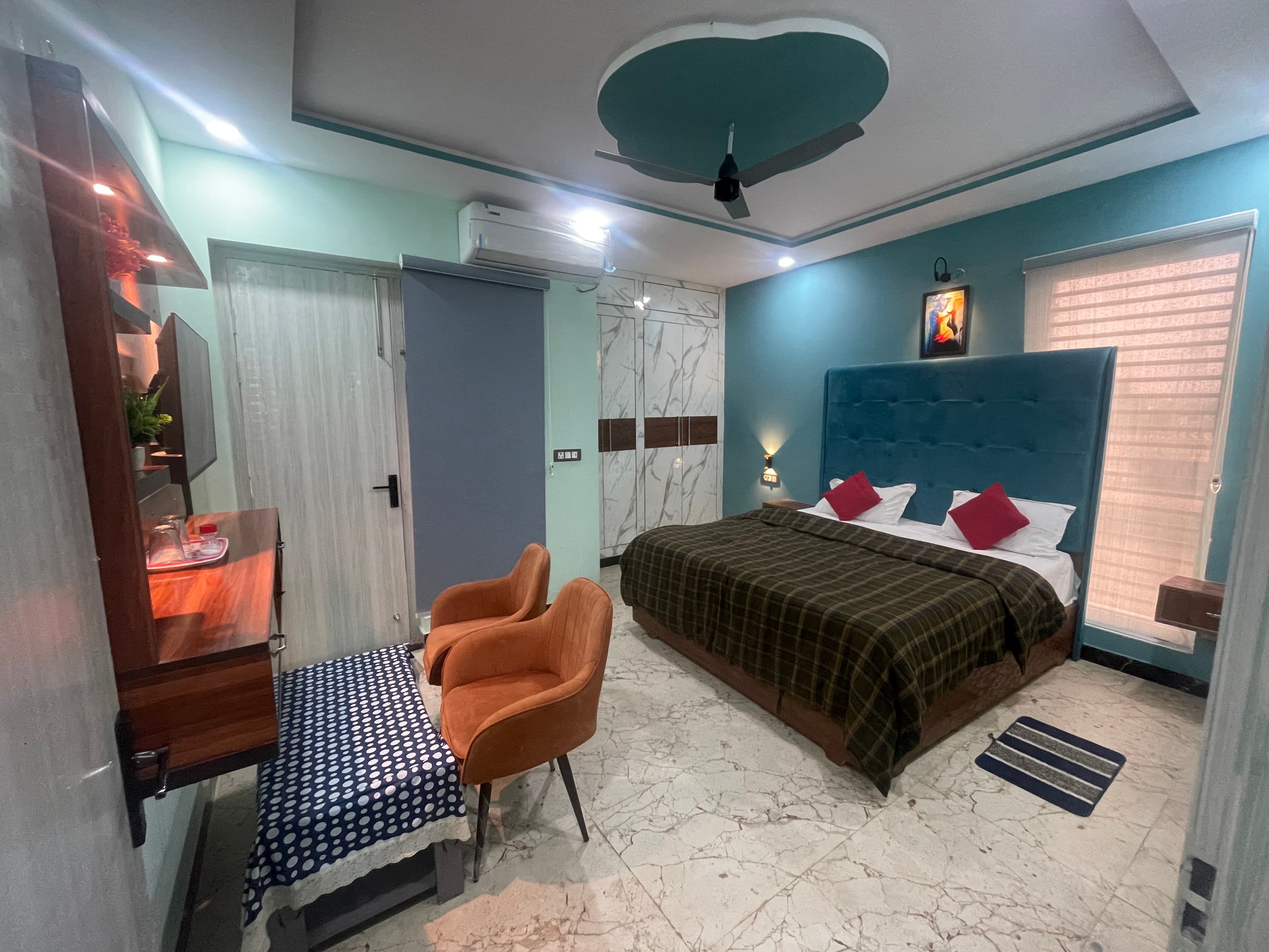 Deluxe AC Room at VMP Villa โ teal accent wall with king bed and seating area