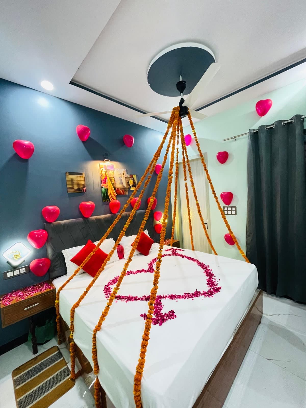 Romantic room decoration โ heart balloons, marigold garlands and rose petals on bed