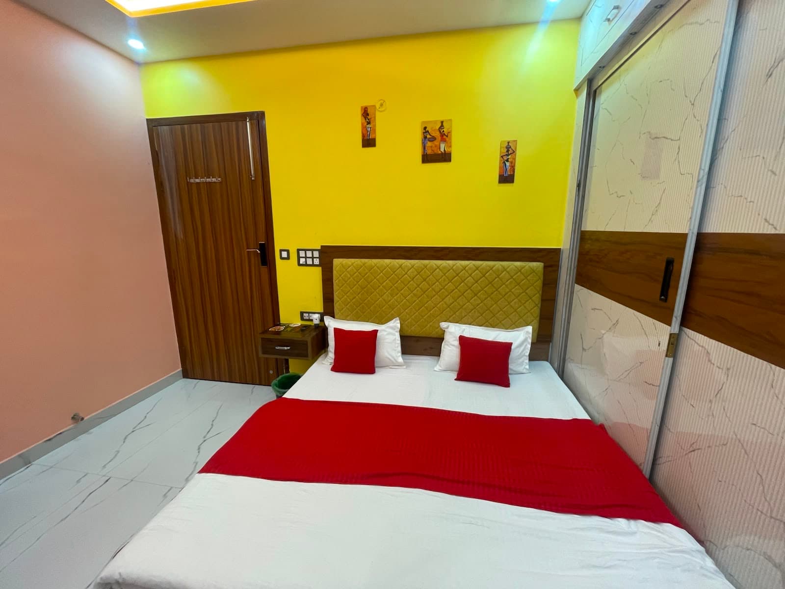 Standard AC Room at VMP Villa โ king bed with yellow accent wall and red pillows